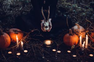 Une sorcière célébrant Halloween avec citrouilles et bougies dans une forêt