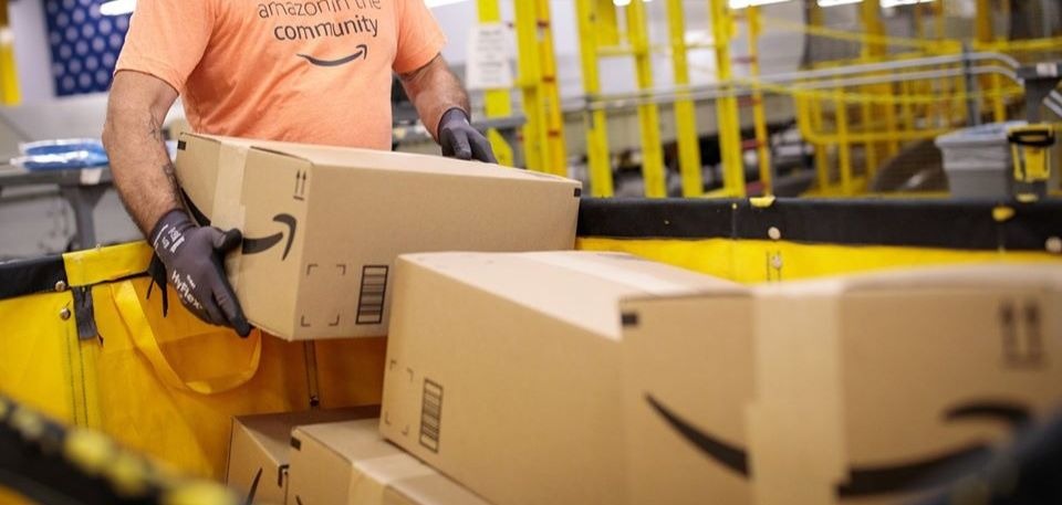 Un employé soulevant des cartons dans un entrepôt d'Amazon.