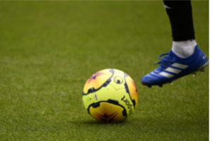 Le pied d'un footballeur devant une balle.